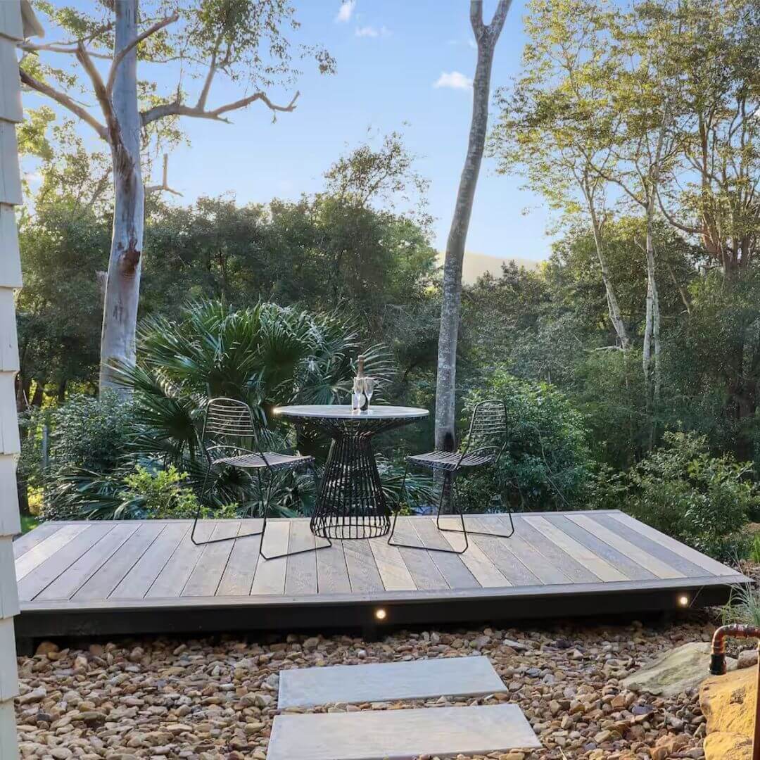 A small outdoor table sitting on a deck overlooking the bush